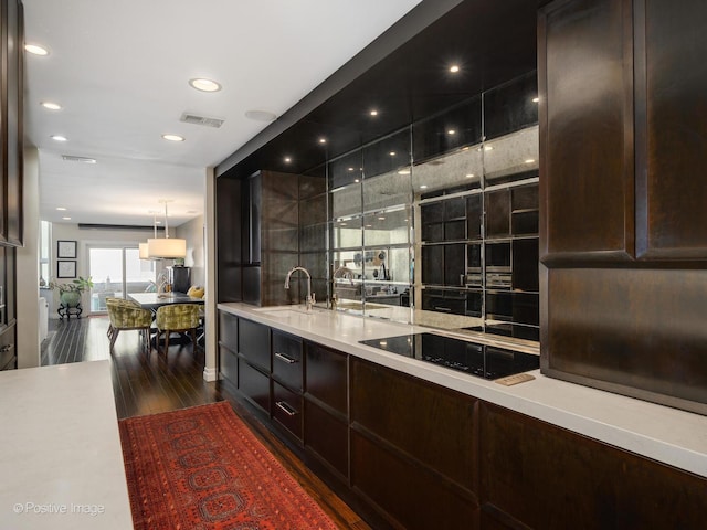 bar featuring black electric stovetop, recessed lighting, visible vents, dark wood-type flooring, and a sink