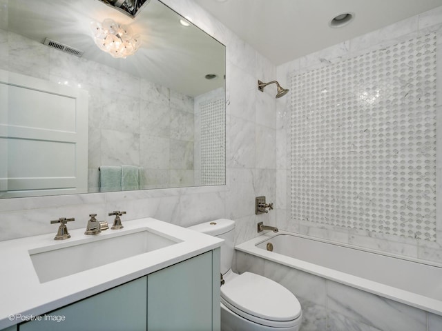 bathroom with tile walls, bathing tub / shower combination, visible vents, toilet, and vanity