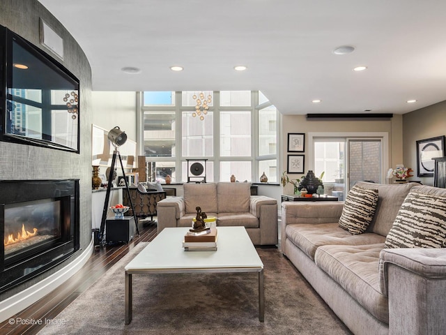 living area featuring dark wood-type flooring, a glass covered fireplace, and recessed lighting