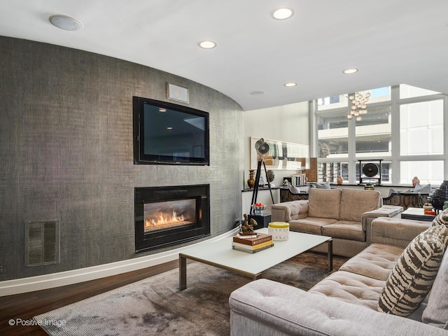 living area with recessed lighting, visible vents, a glass covered fireplace, wood finished floors, and baseboards