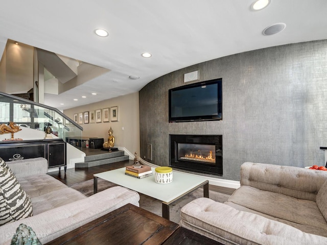 living area with recessed lighting, wood finished floors, baseboards, stairway, and a glass covered fireplace