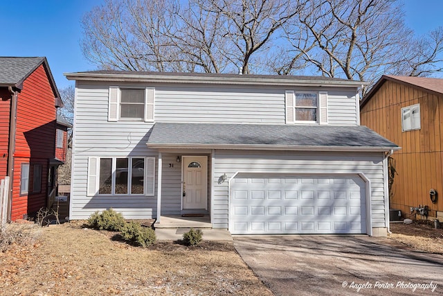 traditional-style house with central air condition unit, driveway, a shingled roof, and a garage