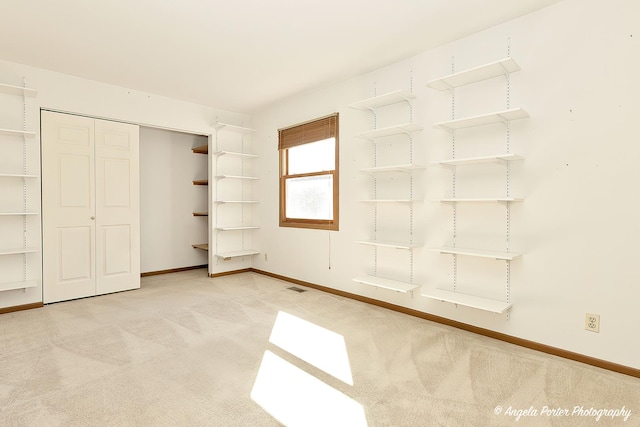 unfurnished bedroom featuring carpet, visible vents, a closet, and baseboards