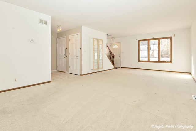 spare room with visible vents, light colored carpet, stairway, and baseboards