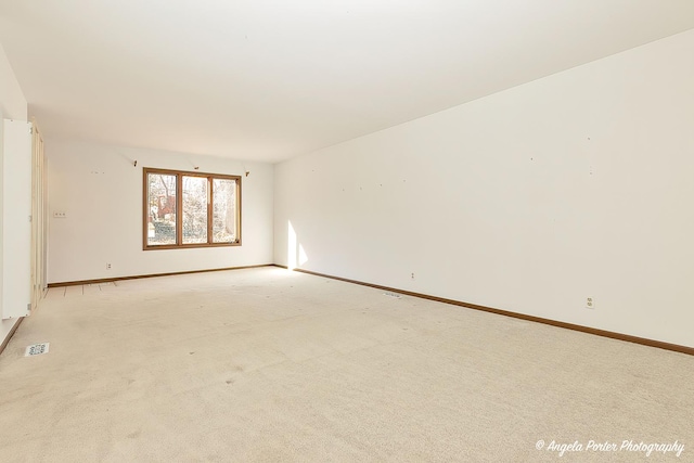 unfurnished room with light colored carpet and baseboards