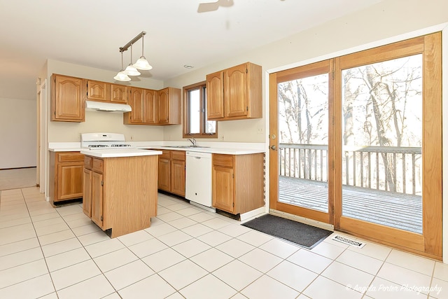 kitchen featuring visible vents, a center island, under cabinet range hood, light countertops, and white appliances