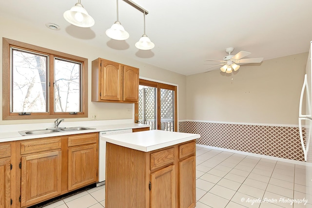 kitchen featuring a wainscoted wall, light tile patterned flooring, a sink, light countertops, and dishwasher