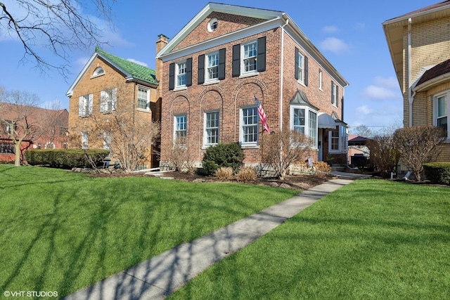 view of front of property featuring brick siding, a chimney, and a front lawn