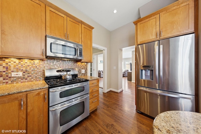 kitchen featuring light stone counters, stainless steel appliances, backsplash, dark wood-type flooring, and baseboards