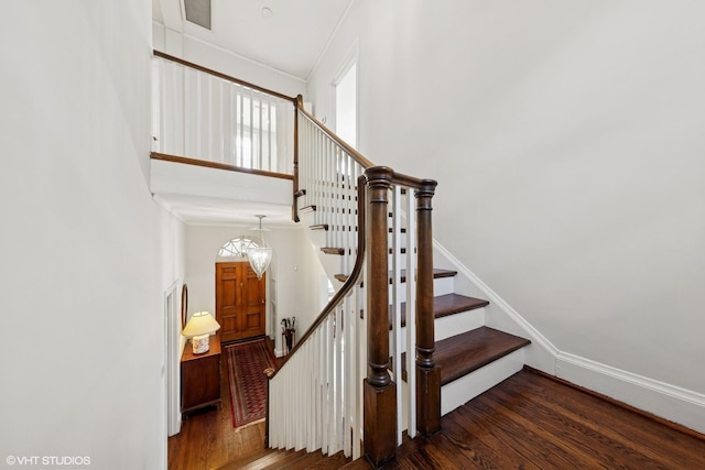 stairs featuring ornamental molding, a towering ceiling, and wood finished floors