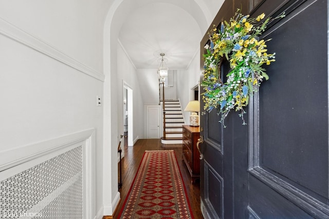 entryway featuring stairway, arched walkways, and dark wood-type flooring