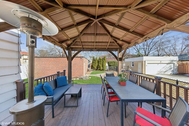 deck with outdoor dining space, fence, an outbuilding, and an outdoor hangout area