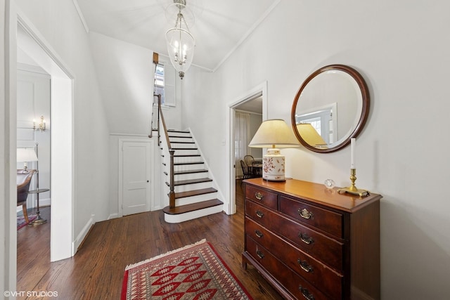 entrance foyer featuring stairs, crown molding, dark wood finished floors, and a notable chandelier