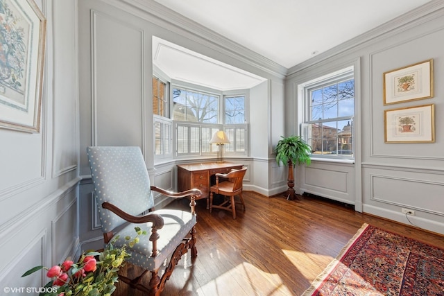 sitting room featuring ornamental molding, wood finished floors, and a decorative wall