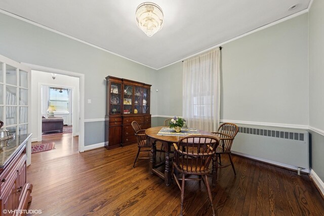 dining room featuring baseboards, radiator heating unit, ornamental molding, and wood finished floors