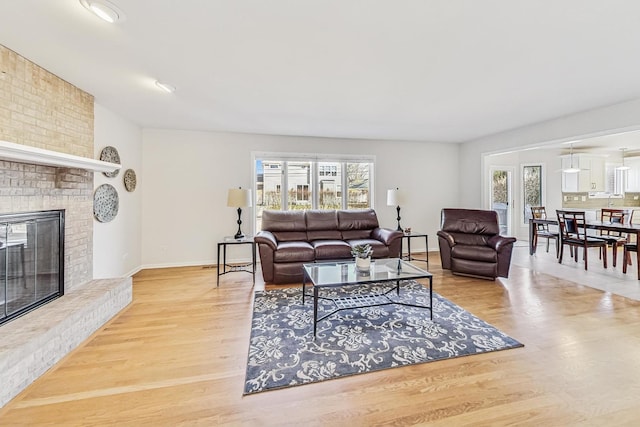 living area featuring baseboards, a healthy amount of sunlight, a fireplace, and light wood finished floors