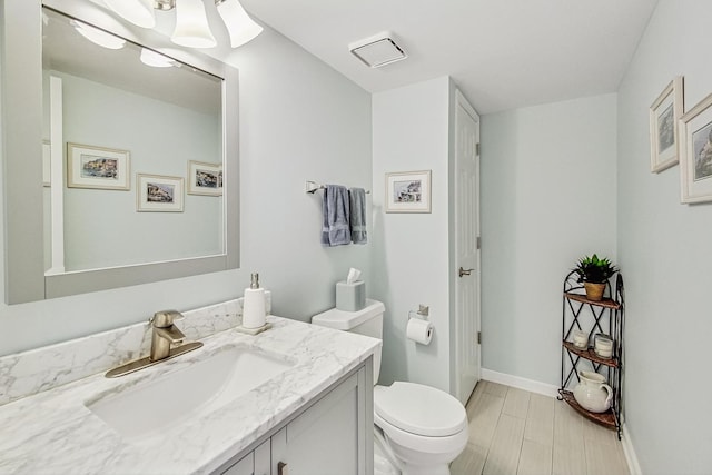 bathroom with toilet, baseboards, and vanity