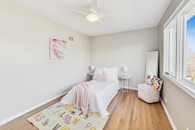 bedroom with light wood-style flooring, visible vents, ceiling fan, and baseboards