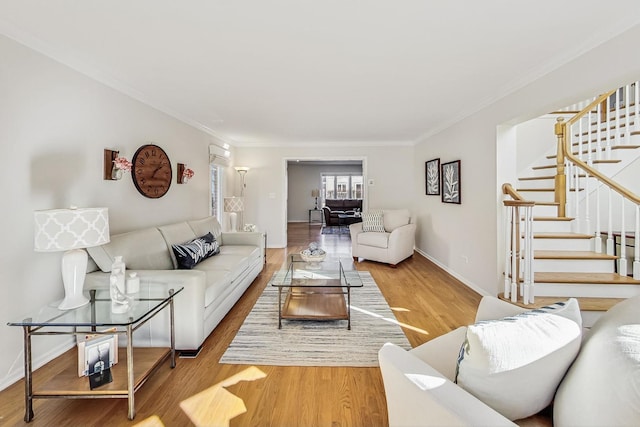 living room with ornamental molding, stairway, baseboards, and wood finished floors