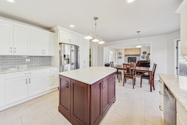 kitchen featuring appliances with stainless steel finishes, white cabinets, hanging light fixtures, and backsplash