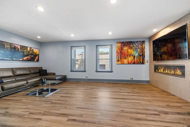 living area featuring a fireplace, baseboards, wood finished floors, and recessed lighting