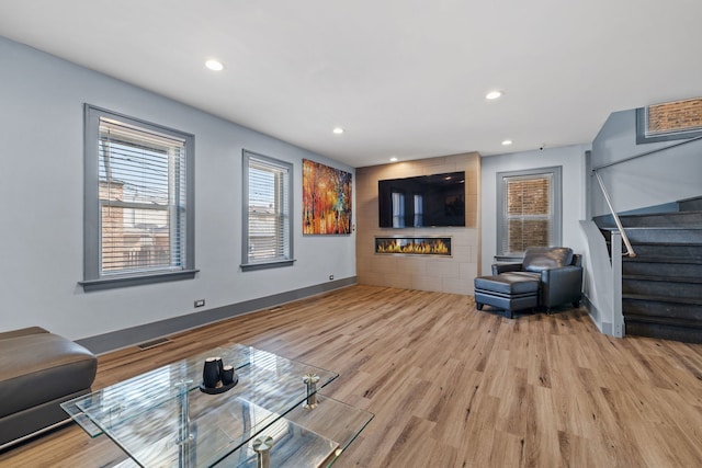 living room featuring recessed lighting, visible vents, light wood-style floors, a large fireplace, and stairs