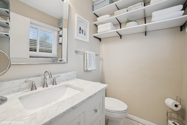 bathroom featuring baseboards, vanity, and toilet