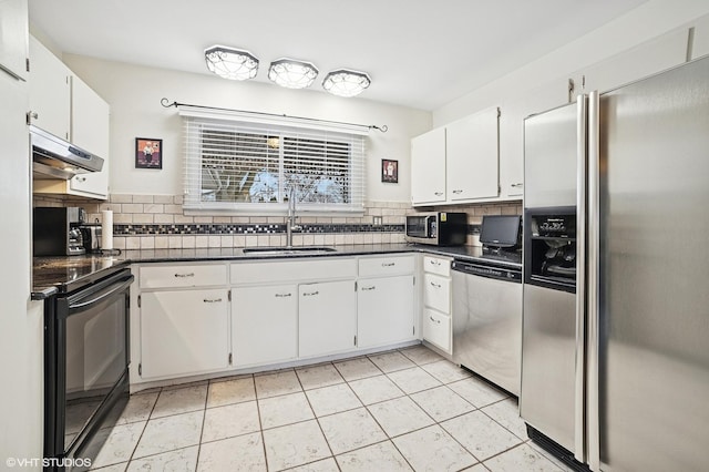 kitchen featuring dark countertops, appliances with stainless steel finishes, under cabinet range hood, white cabinetry, and a sink