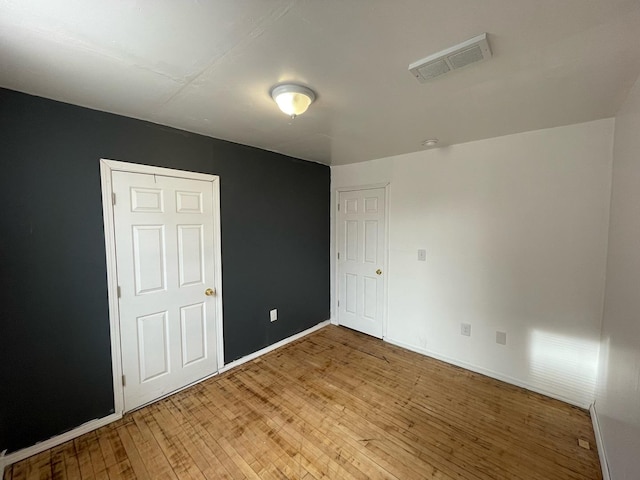 unfurnished bedroom featuring light wood-style floors, baseboards, and visible vents