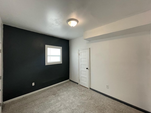 empty room featuring baseboards and light colored carpet