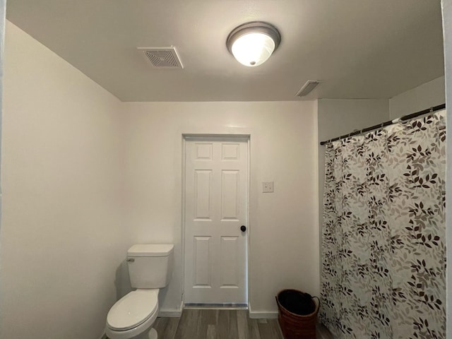 bathroom with toilet, wood finished floors, visible vents, baseboards, and a shower with curtain