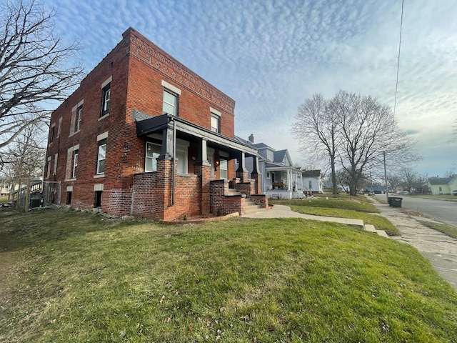 view of home's exterior with a porch, brick siding, and a lawn