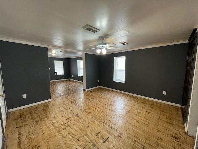 spare room featuring a ceiling fan, visible vents, crown molding, and light wood-style flooring