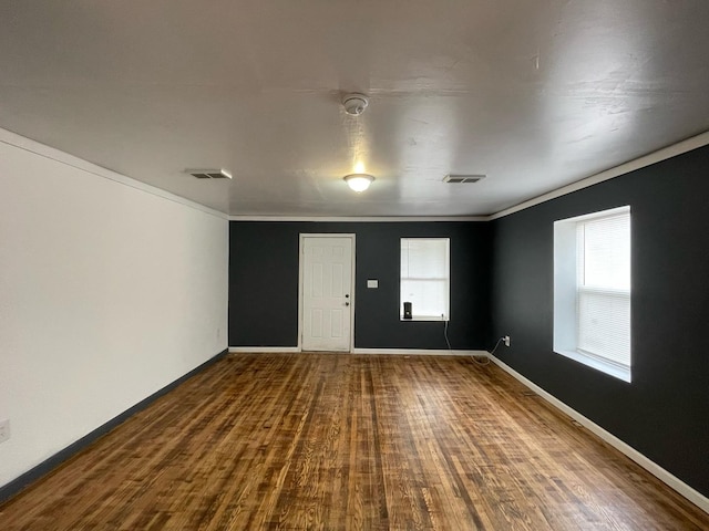 spare room with dark wood-type flooring, visible vents, and baseboards