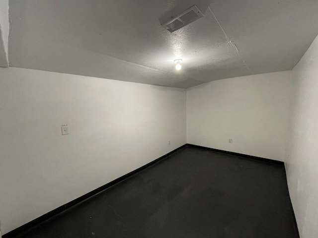 empty room with concrete flooring, visible vents, and baseboards