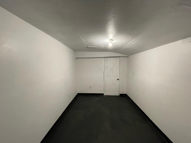 spare room with lofted ceiling, visible vents, concrete floors, and baseboards