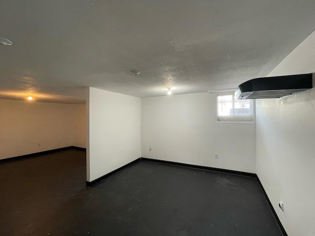 below grade area with baseboards and a textured ceiling