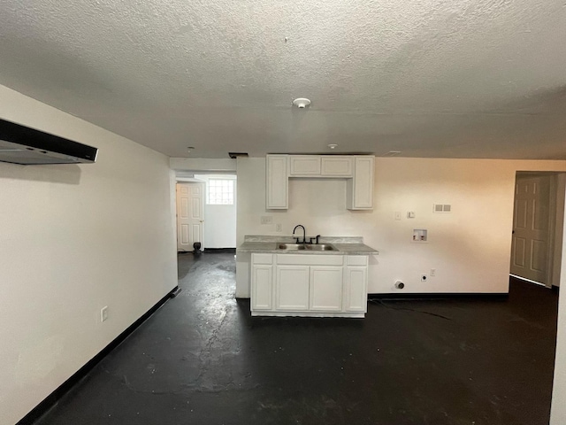 kitchen with white cabinets, a sink, and baseboards