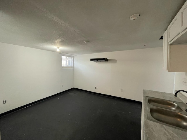 interior space with a textured ceiling, a sink, and baseboards