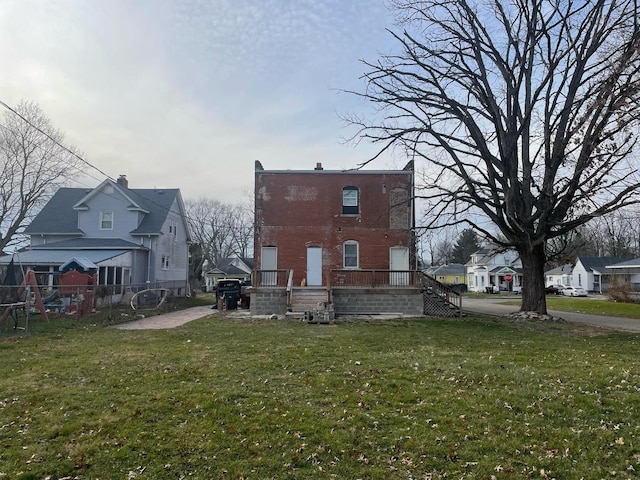 back of property featuring a lawn, a patio, a residential view, fence, and brick siding