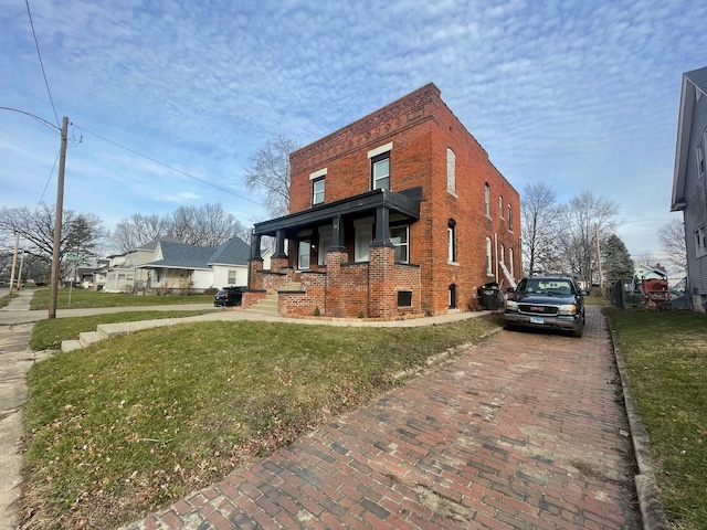 view of home's exterior featuring a yard, decorative driveway, and brick siding