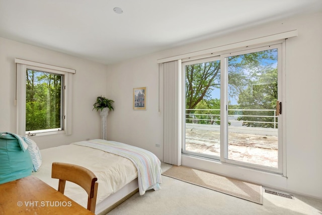 carpeted bedroom featuring access to exterior, visible vents, and multiple windows