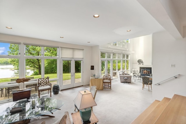 living area featuring a glass covered fireplace, french doors, light colored carpet, and recessed lighting