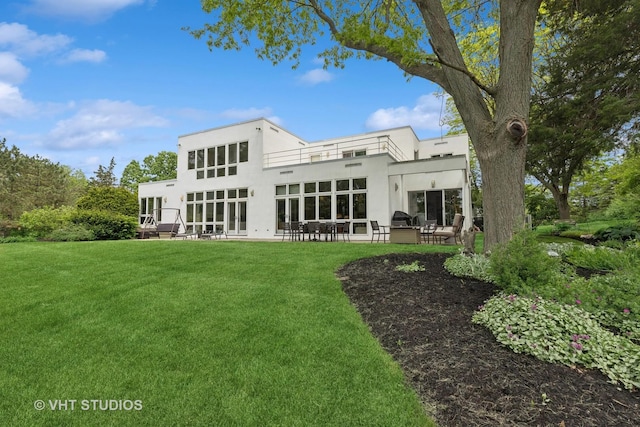 back of property with a patio area, a lawn, and stucco siding