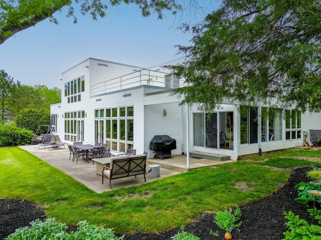 back of property with a patio area, a yard, a sunroom, and stucco siding