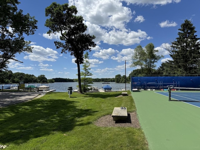 view of community featuring a yard, a dock, a water view, and fence