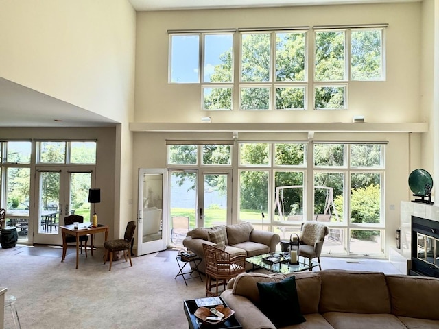 living room featuring carpet, a high ceiling, a tiled fireplace, and french doors