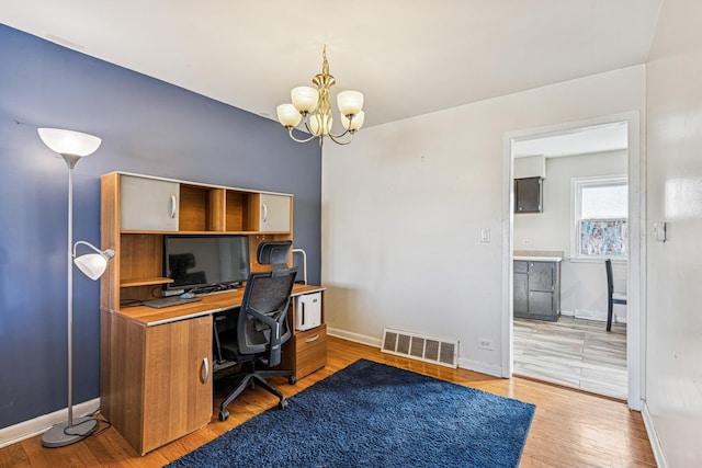 home office with baseboards, visible vents, a notable chandelier, and light wood finished floors