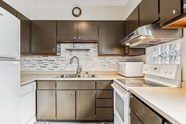 kitchen with light countertops, backsplash, a sink, white appliances, and under cabinet range hood