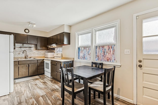 kitchen featuring light countertops, white appliances, a sink, and under cabinet range hood